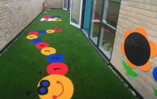 14-1 Bright outdoor play area at Monkey Puzzle Day Nursery Stoke Newington featuring colorful hopscotch and alphabet flower decor, ideal for early childhood learning and development.