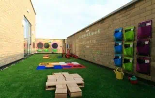 MPStNewington-1729 Colorful outdoor play area at Monkey Puzzle Day Nursery Stoke Newington with toys, mats, and educational equipment. Safe and engaging environment for children's early childhood development.