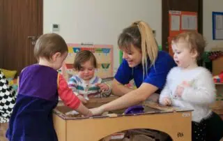 Children playing at Monkey Puzzle Day Nursery Stoke Newington, engaging in educational activities with caregivers in a colorful learning environment.