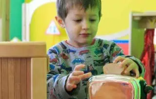 Colorful childcare environment at Monkey Puzzle Day Nursery Stoke Newington, with a young boy engaging with educational toys and activities.