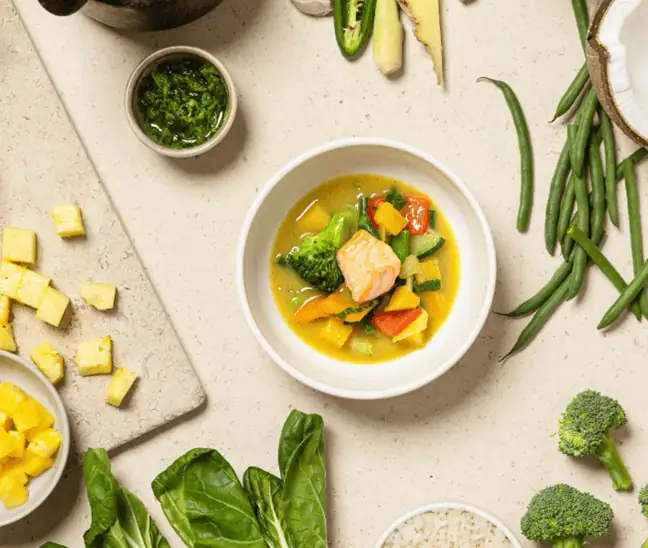 Fresh vegetable soup with colorful broccoli, carrots, and zucchini on a light background. Healthy, nutritious meal perfect for children at Monkey Puzzle Day Nursery Stoke Newington.
