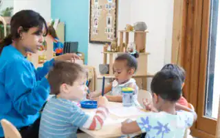 Brightly lit classroom at Monkey Puzzle Day Nursery Stoke Newington with diverse children engaged in creative activities, fostering learning and development in a nurturing environment.