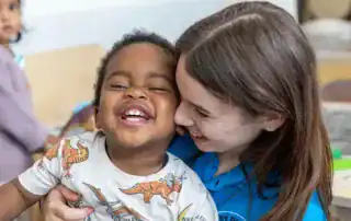 Bright and cheerful children at Monkey Puzzle Day Nursery Stoke Newington enjoying a happy moment with a caregiver.
